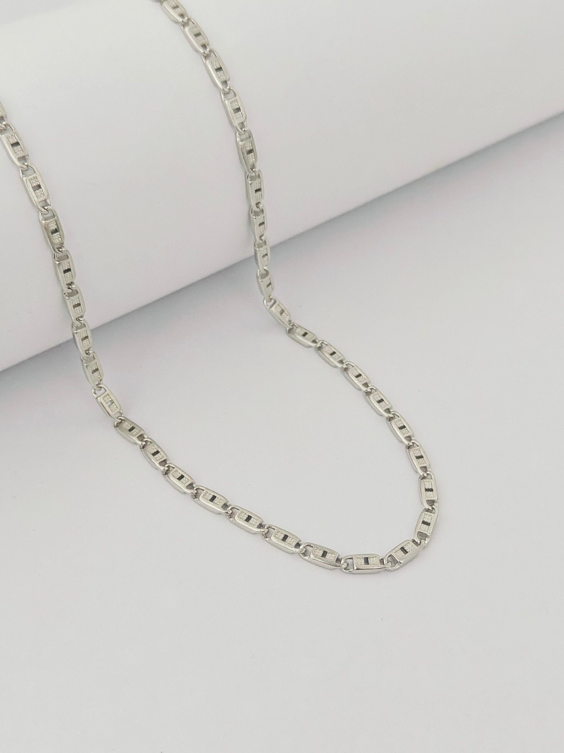 Silver chain necklace on a light gray background